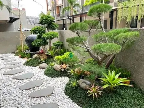 Jalan batu pipih di atas kerikil putih dengan bonsai