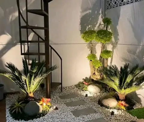 Taman di bawah tangga spiral dengan batu, kerikil, dan sikas